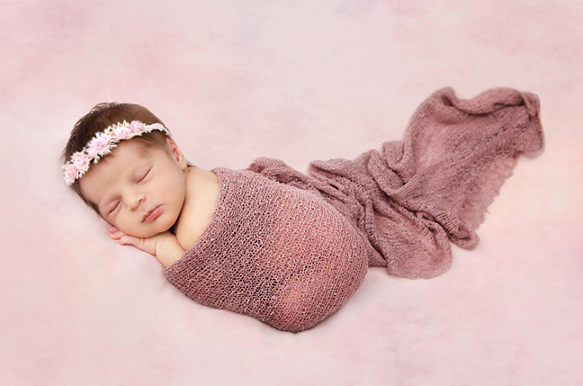 newborn photo shoot of a baby girl in a pink baby wrap